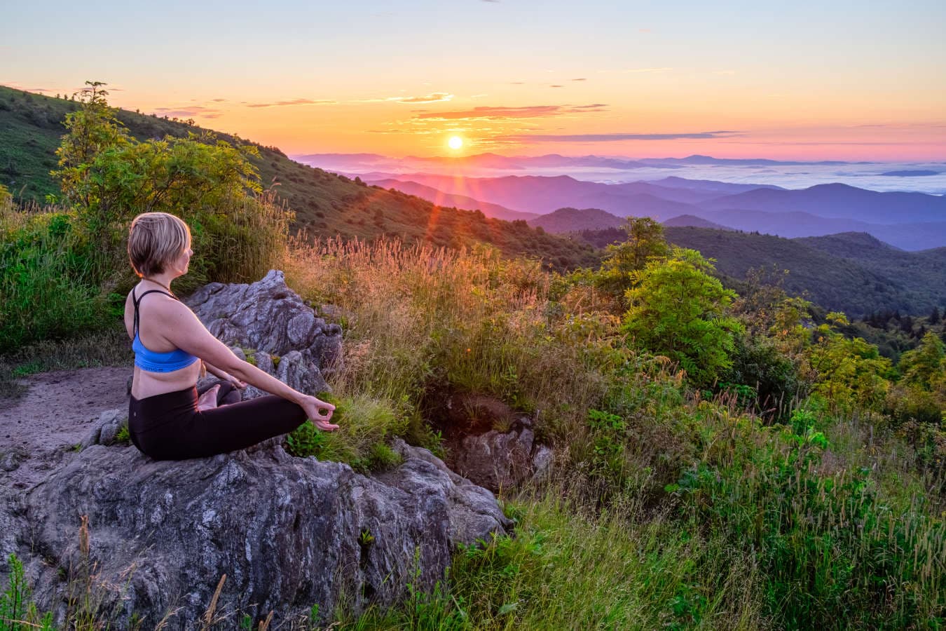 Meeting Planner's Guide to Group Wellness Activities in Asheville, N.C. A woman does yoga as the sun rises over Ashville's mountains