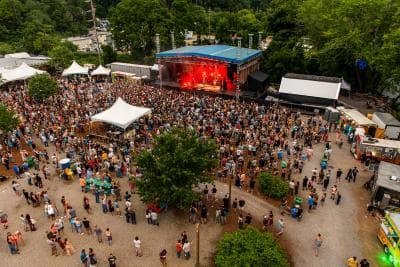 Aerial photo of a crowd surrounded outside near a stage at Salvage Station Aerial photo of a crowd surrounded outside near a stage at Salvage Station