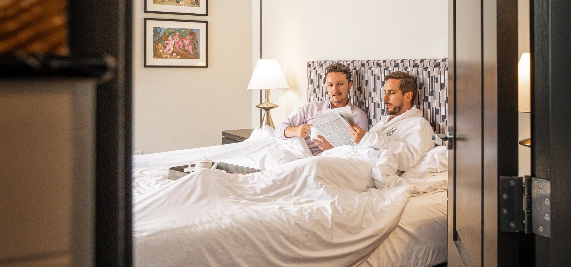 Partners lounging in bed at hotel in Asheville Partners lounging in bed at hotel in Asheville