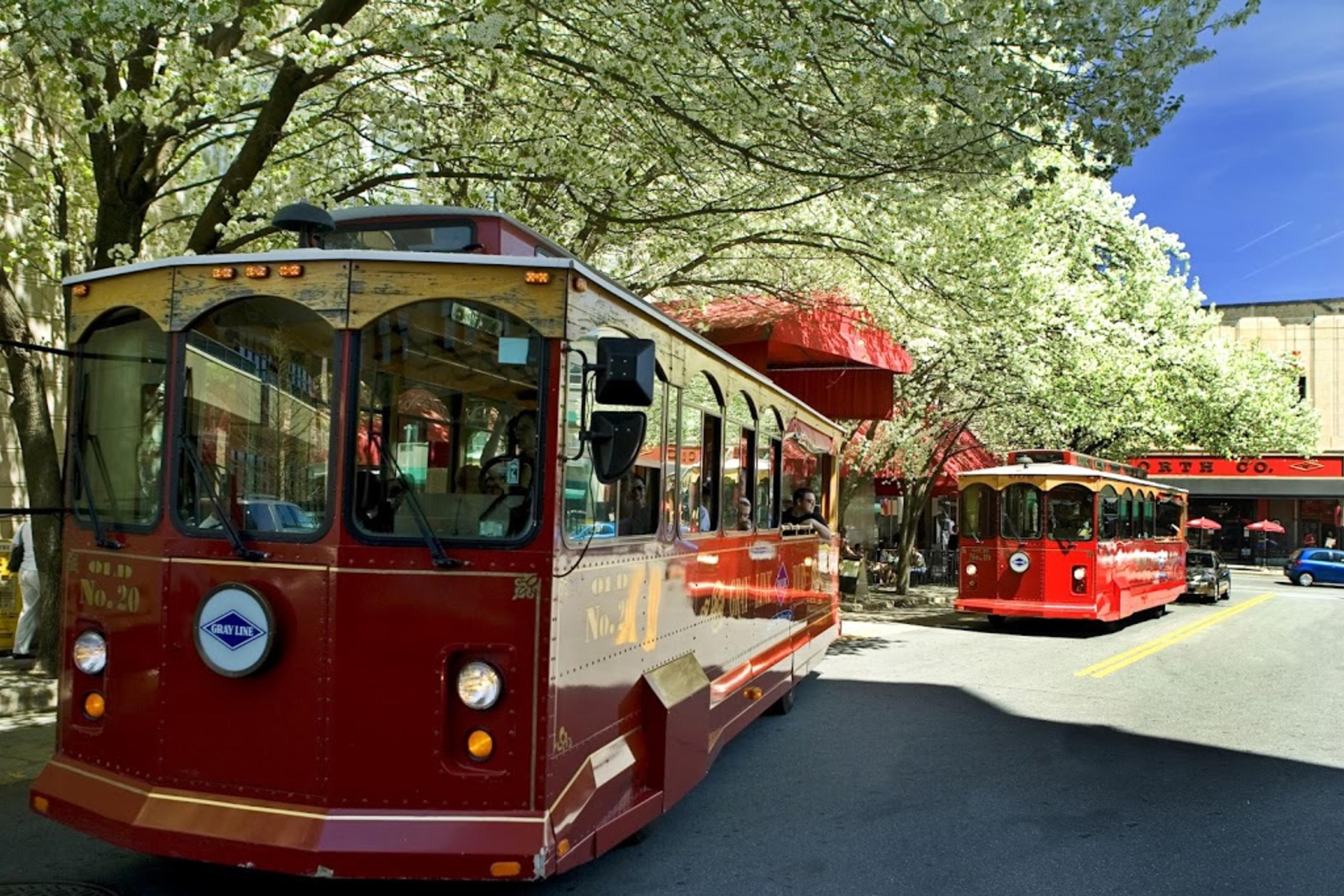 5 Awesome Ways to Explore Asheville’s Rich History a trolly bus is parked on a charming street with green trees in Asheville