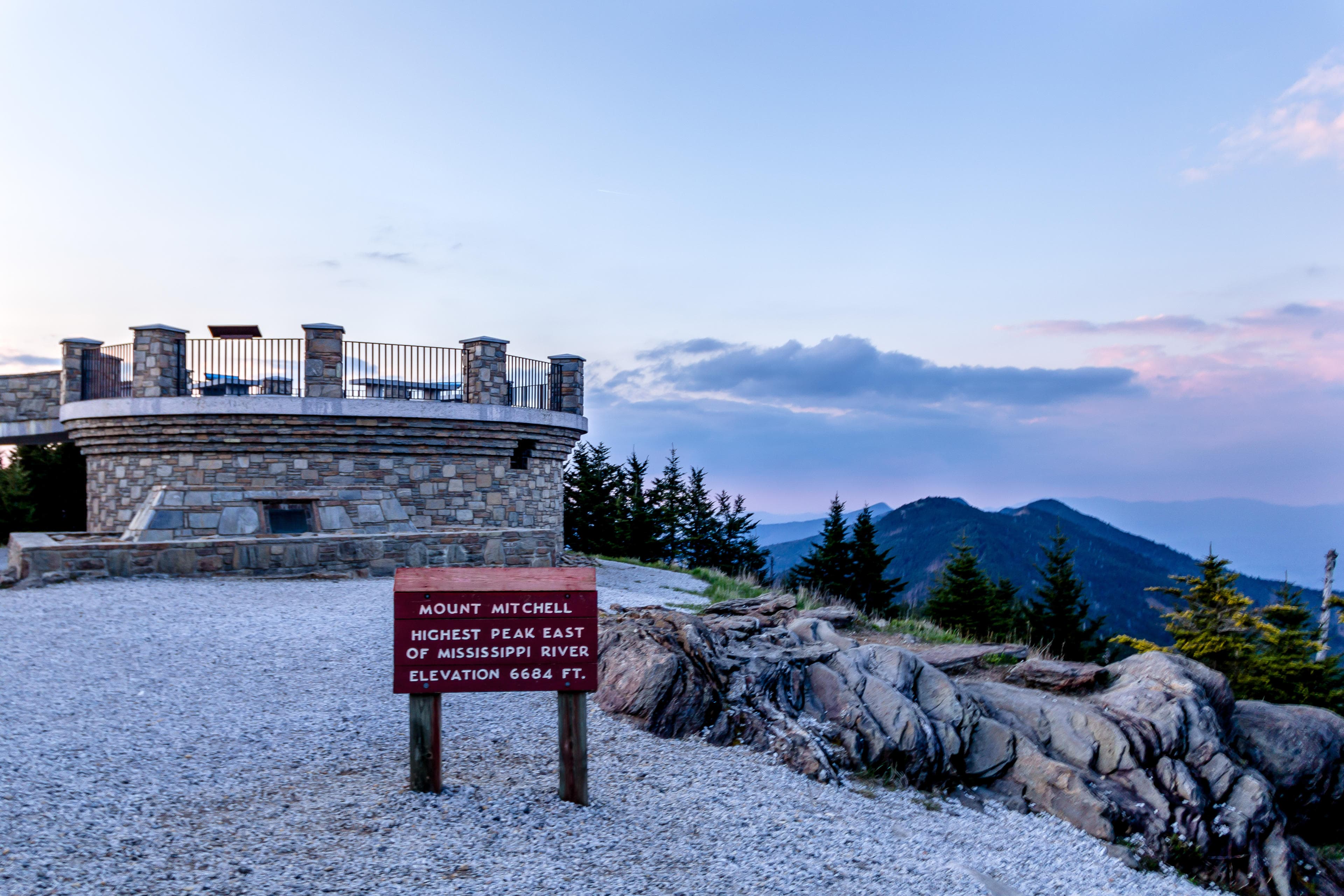 Home of the Highest, Oldest Peaks a sign read "Mt. Mitchell" at sunset, overlooking beautiful mountains