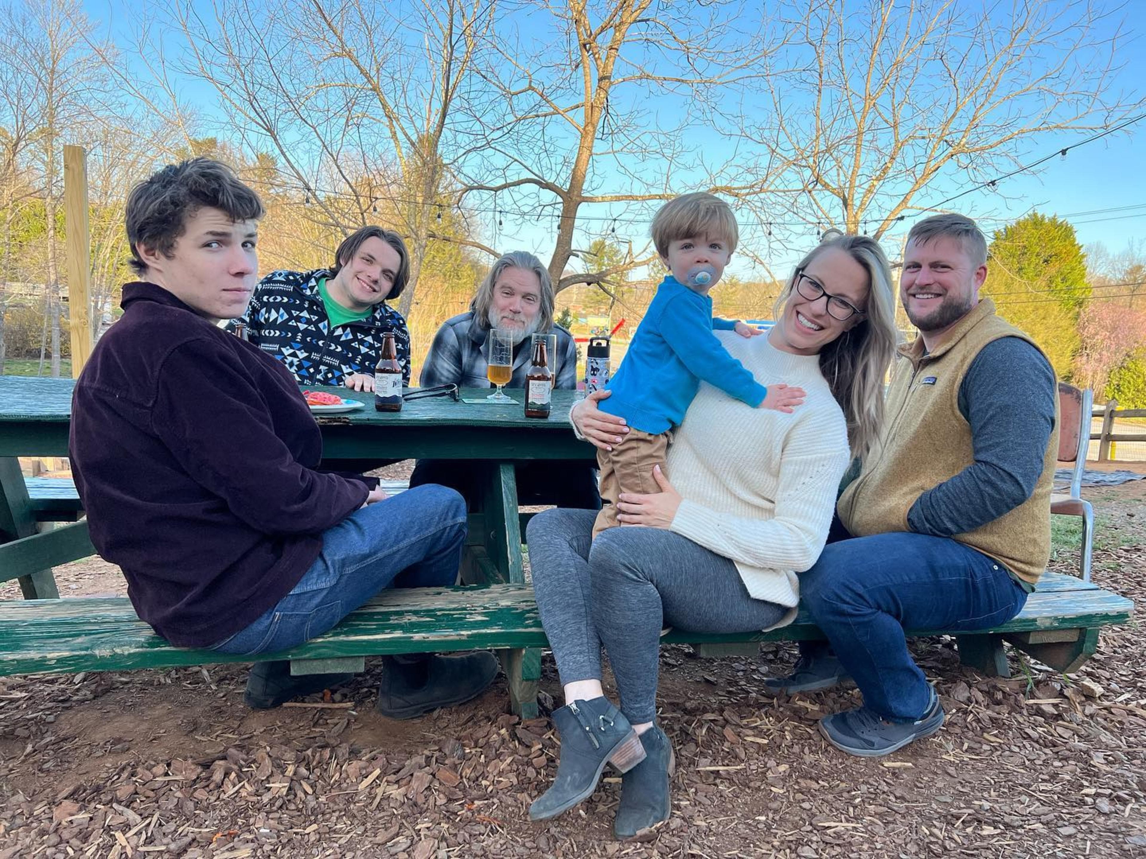 Kid-Friendly Restaurants and Breweries in Asheville, NC a family sits on a park bench smiling.