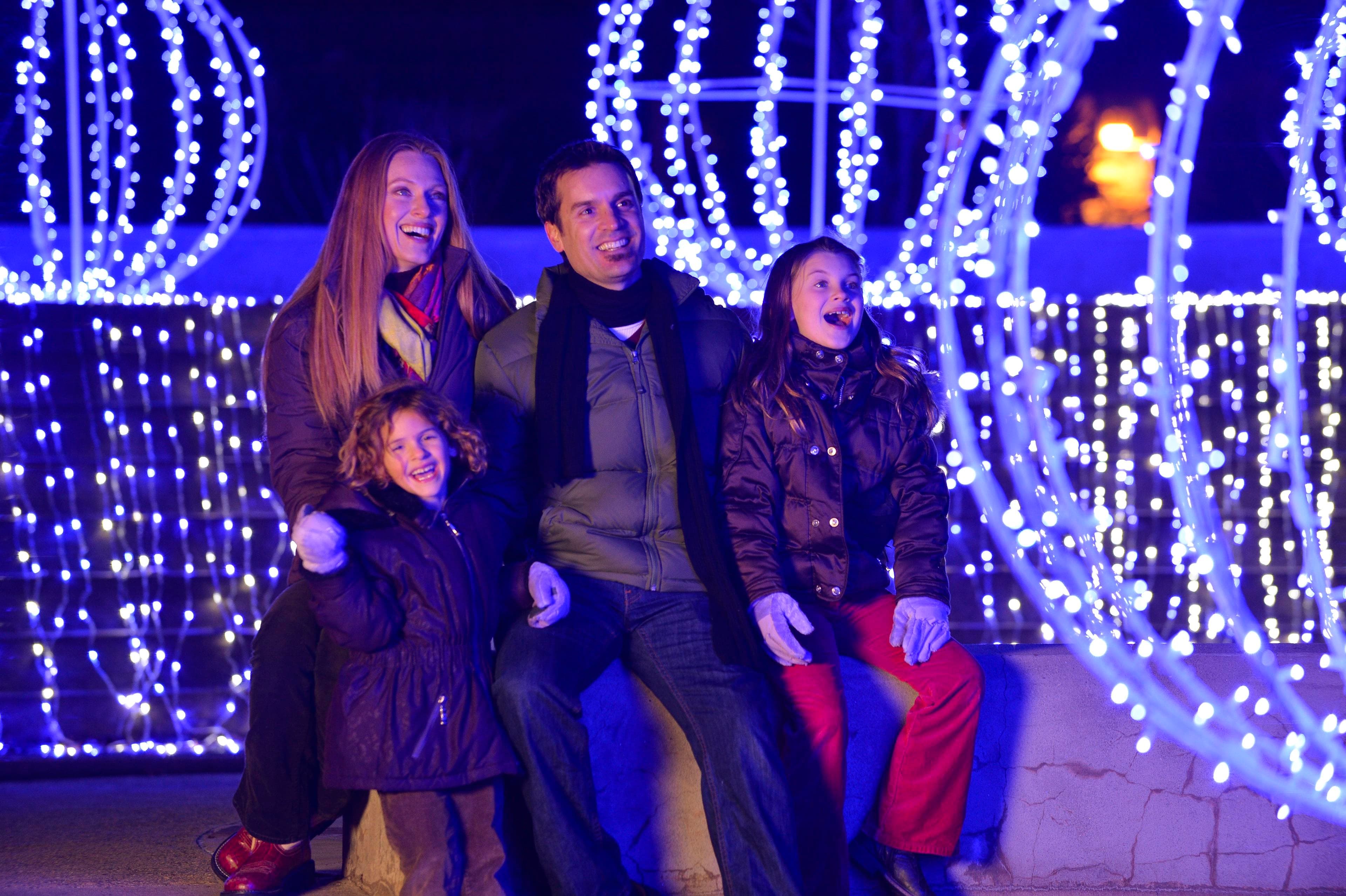 A family is surrounded by a holiday light display A family is surrounded by a holiday light display