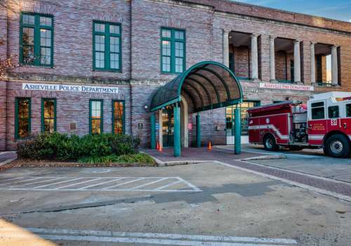 100 Court Plaza, Asheville, NC 28801 This two-story brick-faced building was designed by architect Ronald Green and originally housed the city’s police, fire, and health departments and city jail. The City (Farmers’) Market, one of the finest in the southeast, occupied its lower level. On the Market Street side, note the Roman arch entrance, and the cornucopias reflecting its use as a food market. Two plaques honor Mr. Miller: one embedded in the sidewalk on the Market Street side, and the other to the left of the main entrance to the Police Department. 100 Court Plaza, Asheville, NC 28801 This two-story brick-faced building was designed by architect Ronald Green and originally housed the city’s police, fire, and health departments and city jail. The City (Farmers’) Market, one of the finest in the southeast, occupied its lower level. On the Market Street side, note the Roman arch entrance, and the cornucopias reflecting its use as a food market. Two plaques honor Mr. Miller: one embedded in the sidewalk on the Market Street side, and the other to the left of the main entrance to the Police Department.