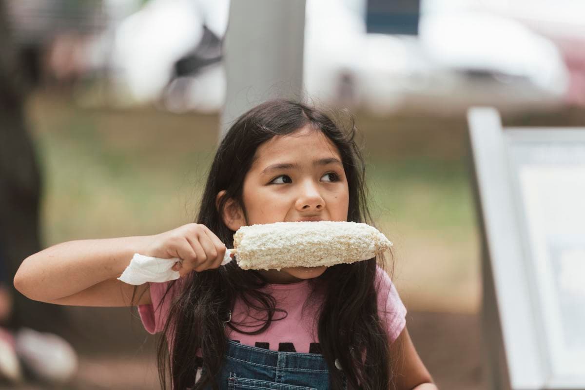Young girl eating Mexican street corn at Hola Asheville Festival Young girl eating Mexican street corn at Hola Asheville Festival